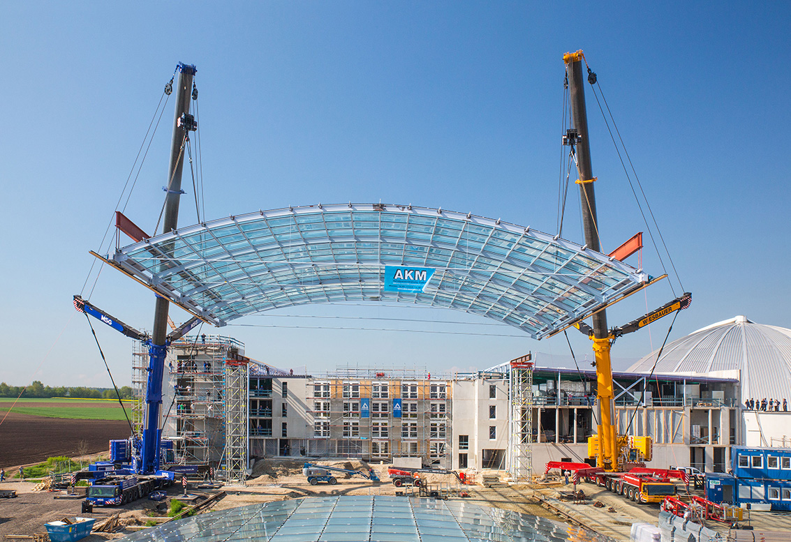 Two Liebherr LTM 1750-9.1 cranes install glass roof:Tandem hoist at Erding thermal water world complex