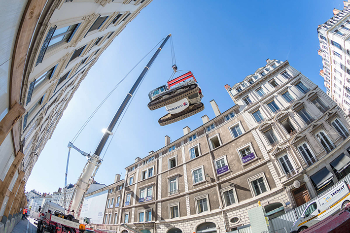 In the very centre of Lyon, a mobile crane lifts two Liebherr crawler excavators for demolition work