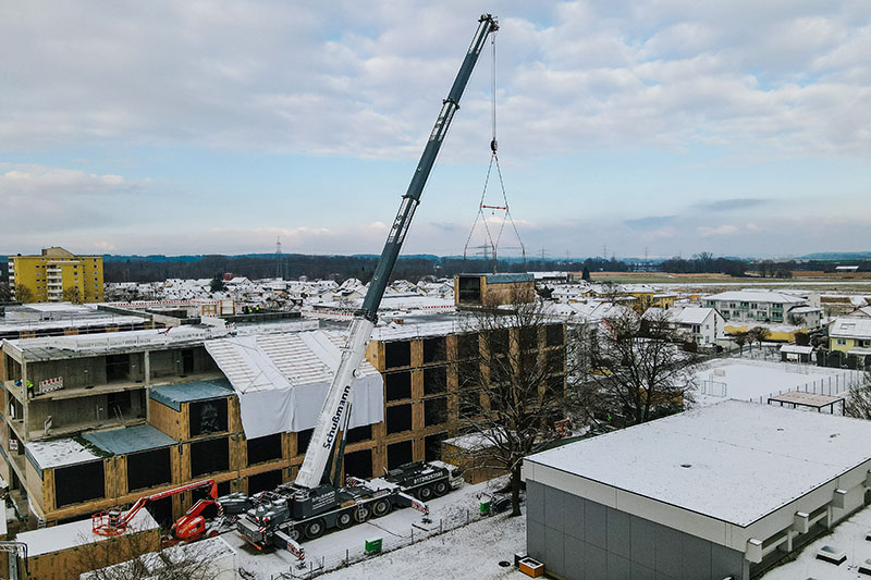 Liebherr LTM 1450-8.1 mobile crane couples timber modules with reinforced concrete carcass for care home