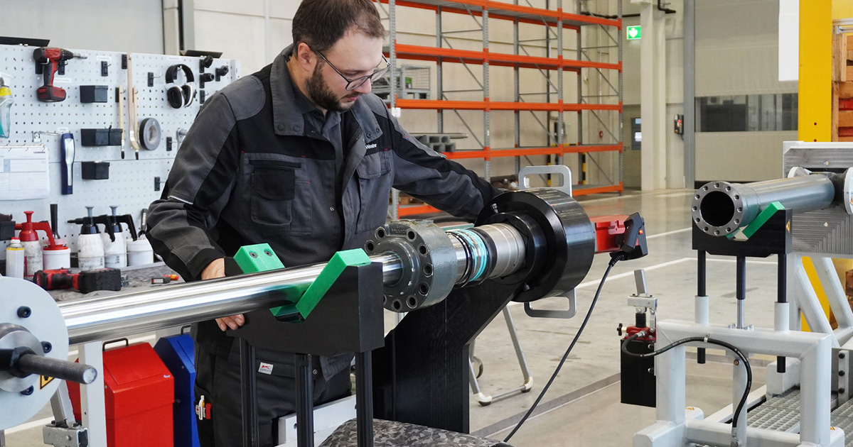 Ein Mann arbeitet an einem Hydraulikzylinder, der auf einer Montagebank von Liebherr montiert ist.