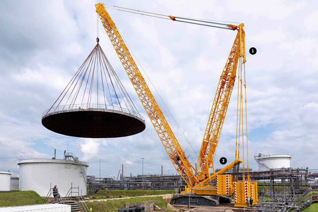 Ein Raupenkran steht auf einer Baustelle und hebt ein sehr großes Bauteil an
