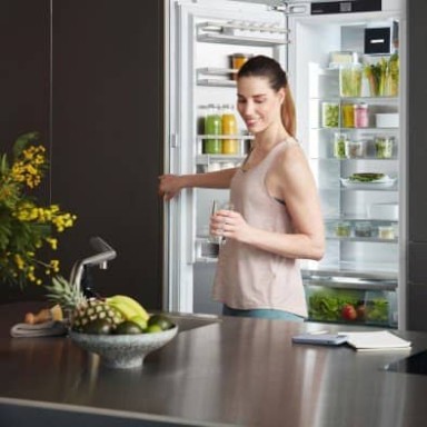 Woman standing in front of side by side appliance with both doors open, reaching to close the left hand door.