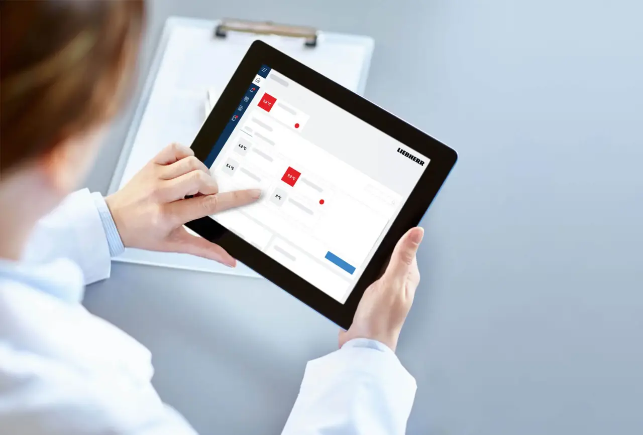 Person in lab coat interacting with SmartMonitoring dashboard on a tablet