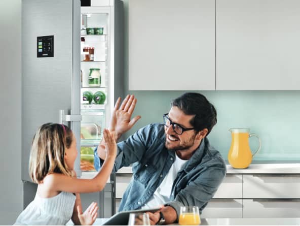 Man and child high fiving in front of fridge freezer with open door