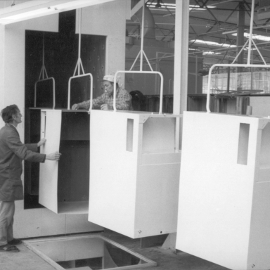 Carcass of a fridge on a line moving with a worker inspecting the fridge carcass