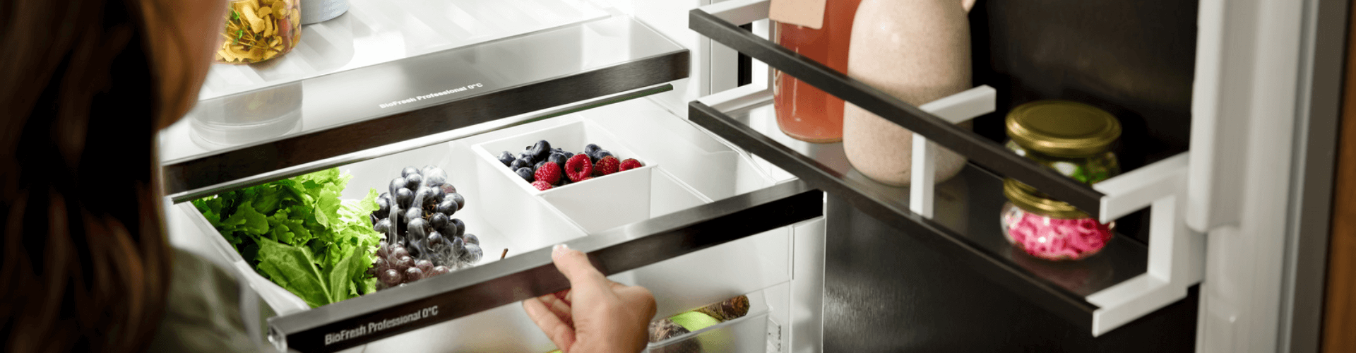 Open door fridge with a person pulling out their drawer showing organised fresh food with the flexsystem being used to organise fruit