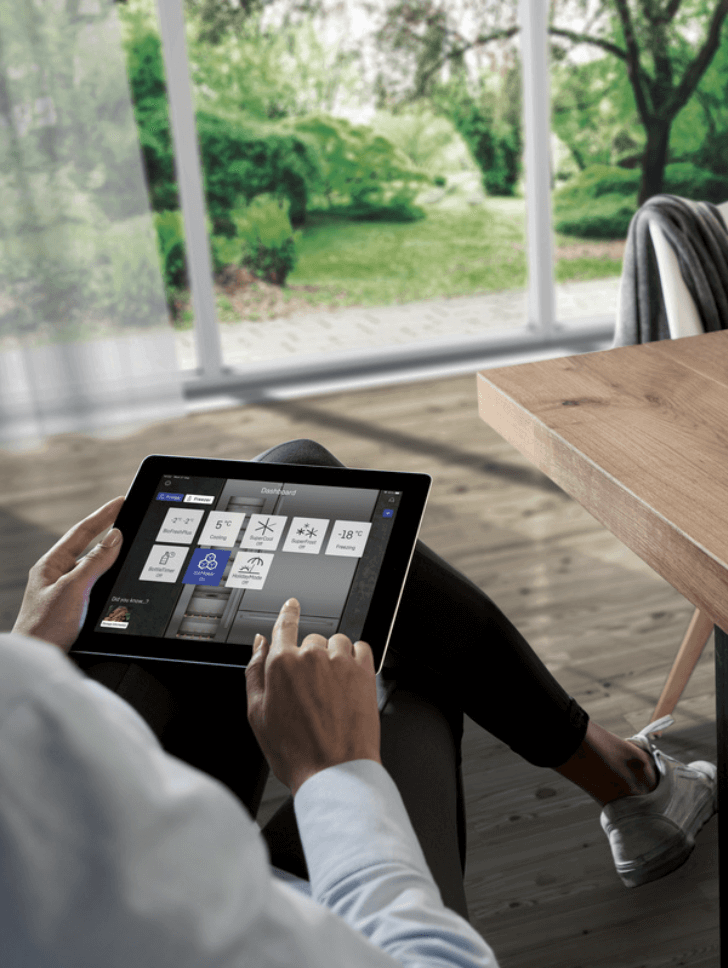 Man using his tablet to change the temperature of his appliance