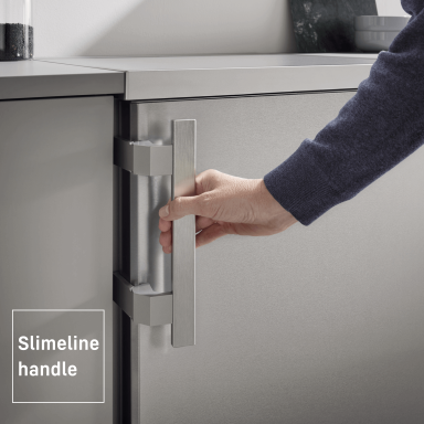 close up of a silver appliance with a person reaching for the door handle