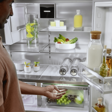 Open door fridge freezer with a man looking at the contents of their appliance