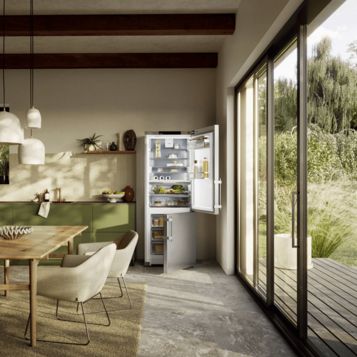 Open door fridge freezer next to large windows showing a back garden in a modern and open airy kitchen