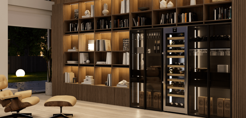 Chic, modern entertaining room with large windows overlooking a garden, featuring a Liebherr wine fridge integrated among glass shelves with books, a comfortable chair with a footstool in the centre, creating a sophisticated and relaxing atmosphere.