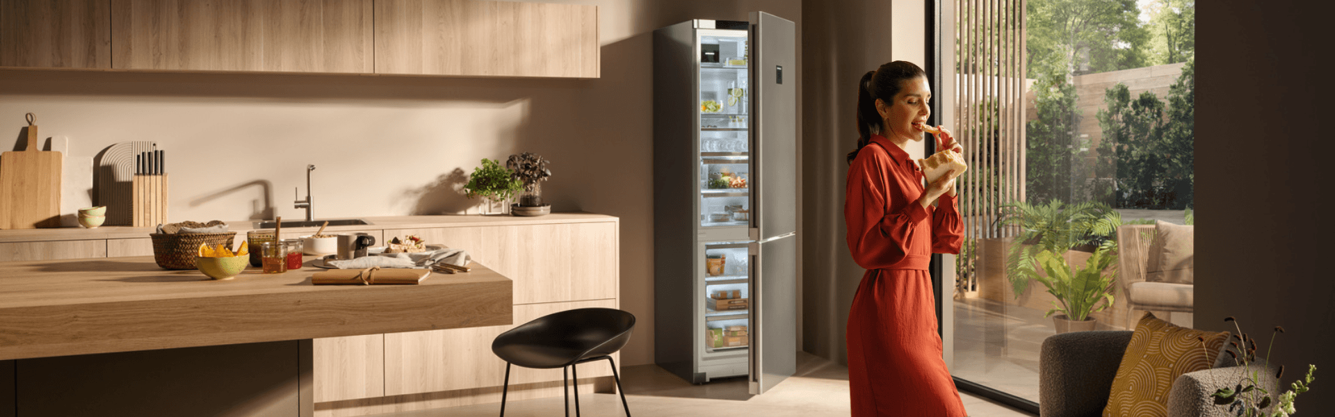 CBNstb 579i Liebherr fridge-freezer Open door Liebherr fridge-freezer CBNstb 579i,in a modern open kitchen, with a woman eating cheese walking towards the chair,