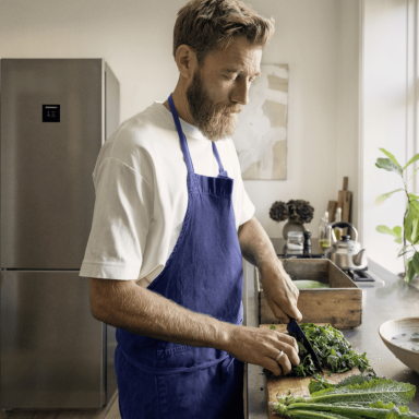 Mikkel Karstad chopping fresh produce in his kitchen with a Liebherr CBNstb 579i fridge-freezer in the background.