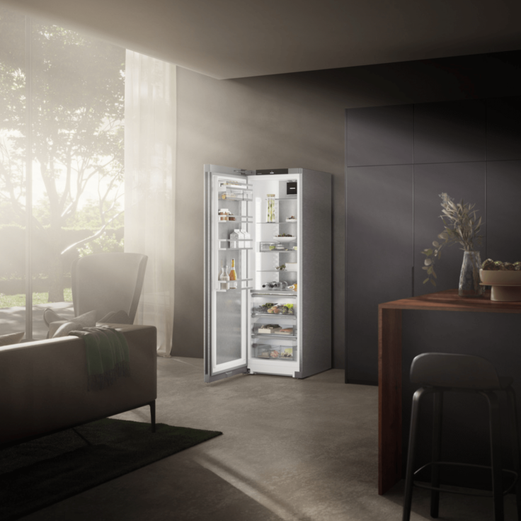 Sunlight beams shining on an open door fridge in a dark toned modern kitchen