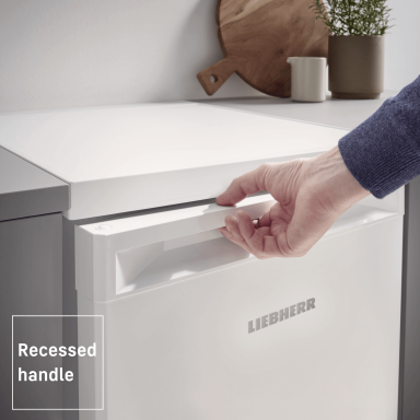 close up of a white appliance with a persons hand reaching for the door handle