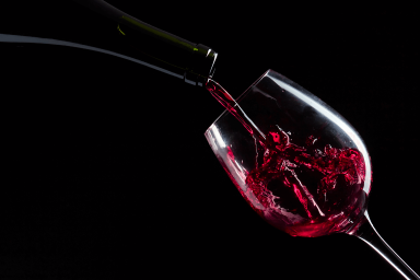 Tilted wine glass being filled with red wine