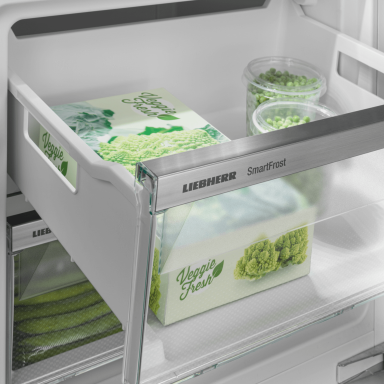 Open drawer with the Liebherr logo and SmartFrost on the trim of the drawer showing frozen food inside