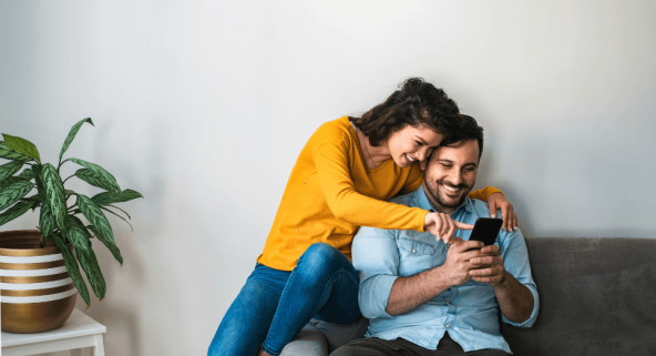 couple on the sofa sharing a phone laughing