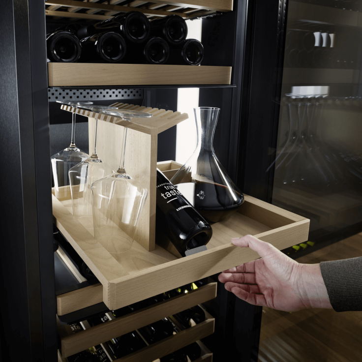 Person pulling out their sommelier board holding a decanter and wine glasses