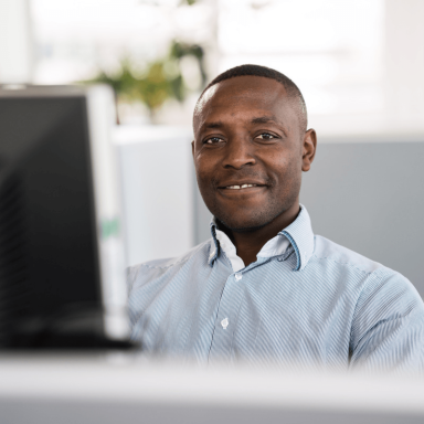 Liebherr professional staff member looking at the camera smiling whilst working on a computer