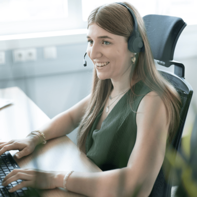Liebherr professional staff member looking at the  their computer screen smiling whilst working with a headset on
