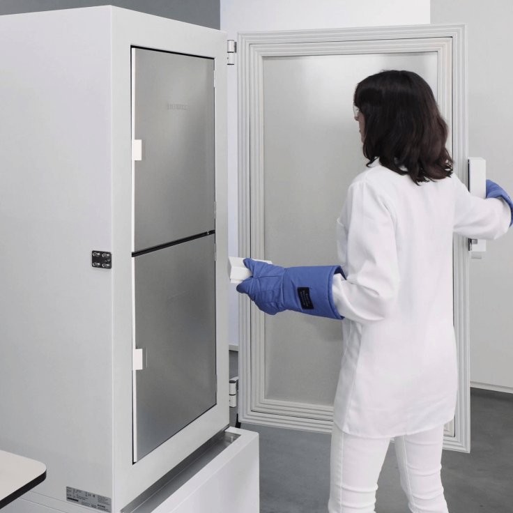 Laboratory personnel opening an ultra low freezer door with blue gloves on