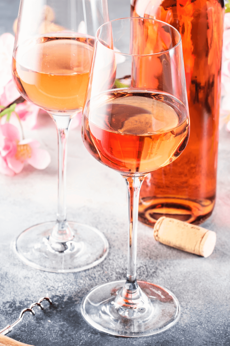 Close up of two wine glasses filled with wine with a wine bottle on the table