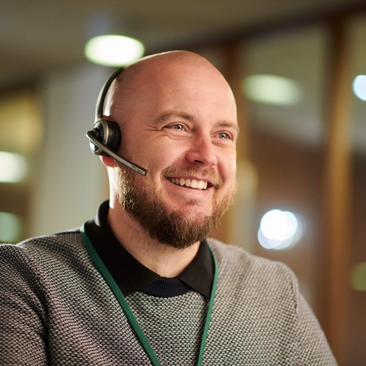 Close up of a bald man smiling on the phone with a headset on