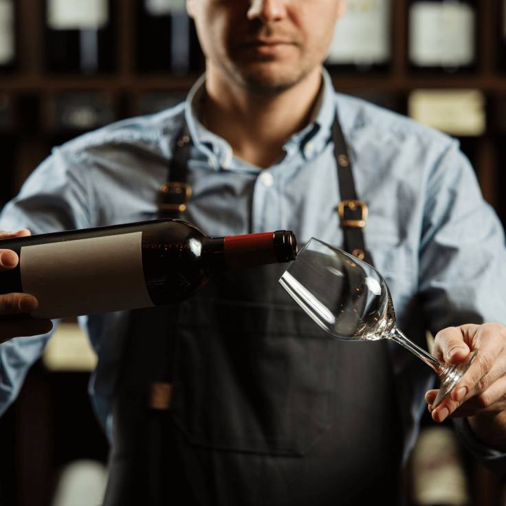 Waiter pouring red wine at the restaurant table