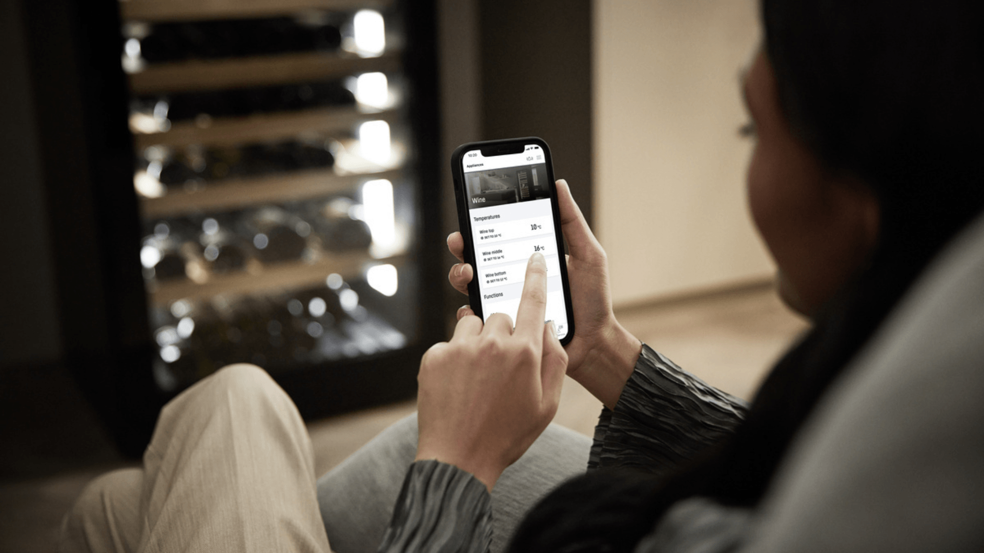 SmartDevice controls on a wine fridge Close-view of a woman using her smartphone to control her wine fridges temperature.