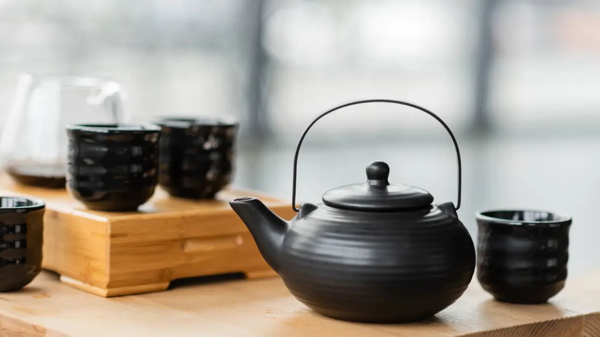 How does tea as an alternative to alcohol create new possibilities? Black teapot with black teacups on a wooden table.