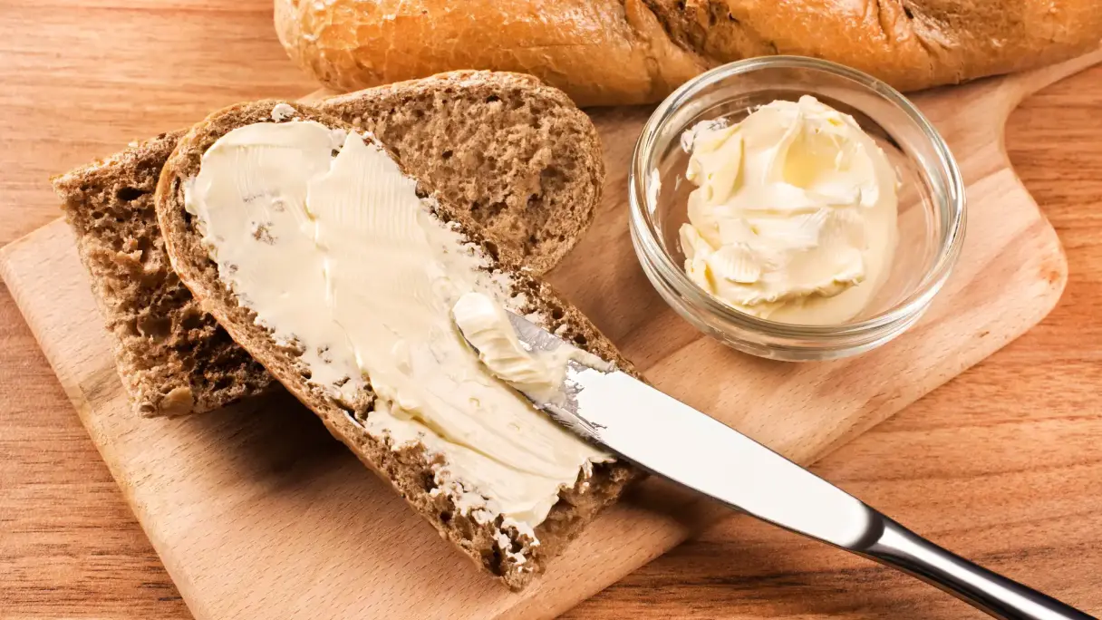 Ballaststoffreiches Brot mit Omega‑3-Margarine Ballaststoffreiches Brot das mit Margarine bestrichen wird.