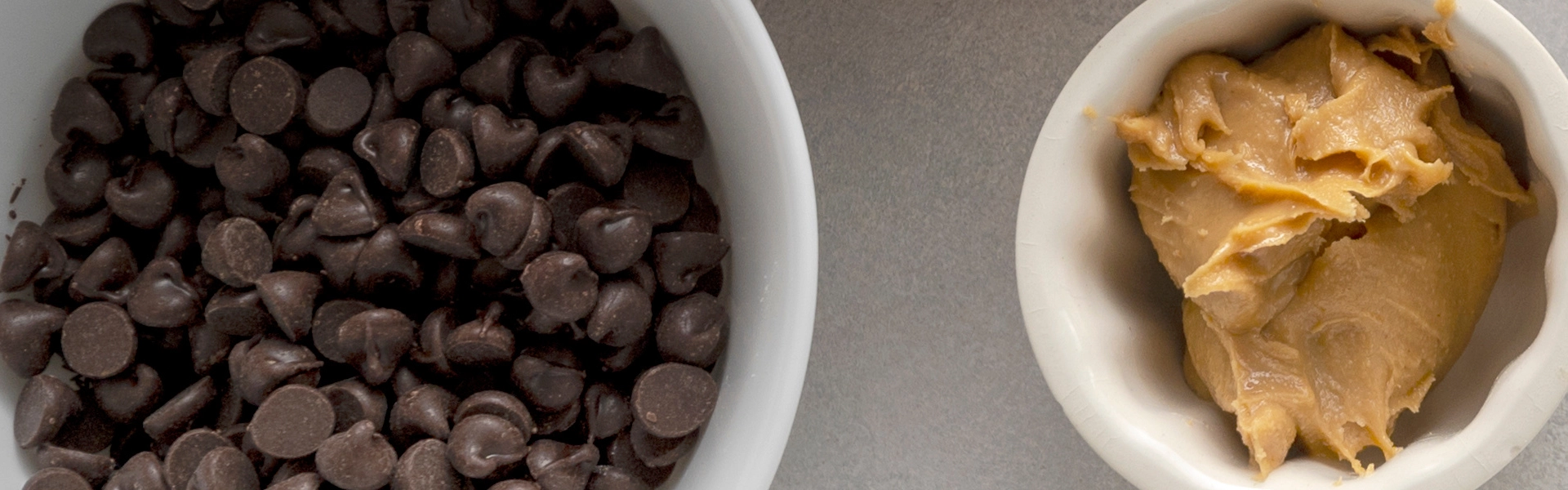 Nahaufnahme von Nussmus und dunklen Schokoladen-Tropfen in kleinen Schälchen