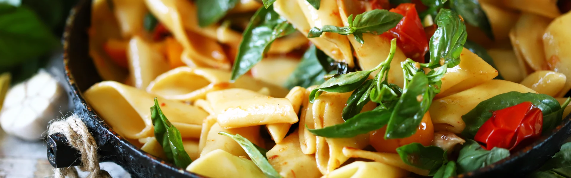 Cooked tagliatelle with fresh basil and tomatoes in a pan, prepared for storage in the fridge.