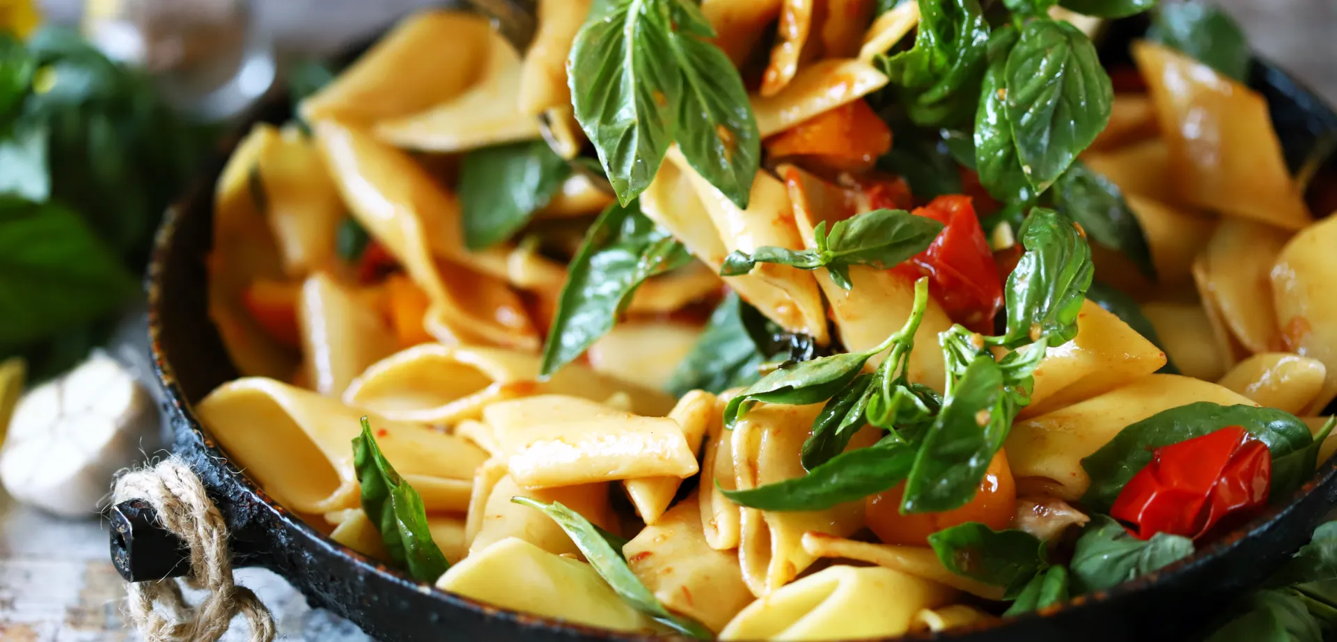 Cooked tagliatelle with fresh basil and tomatoes in a pan, prepared for storage in the fridge.