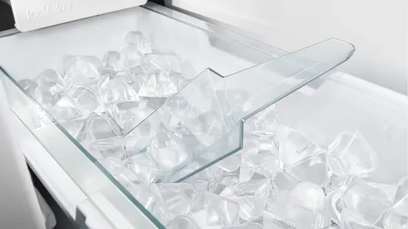 Liebherr Icemaker-Fach im Gefrierschrank, gefüllt mit Eiswürfeln und einer Schaufel, die zwischen den Eiswürfeln steckt.