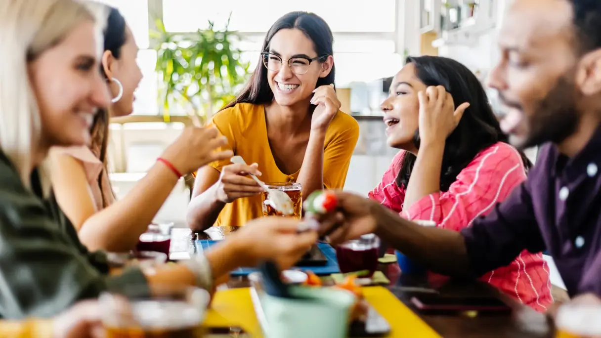 Gemeinsam essen in herausfordernden Zeiten Personen sitzen gemeinsam an einem Tisch, teilen Speisen und Getränke und führen ein Gespräch in entspannter Atmosphäre.