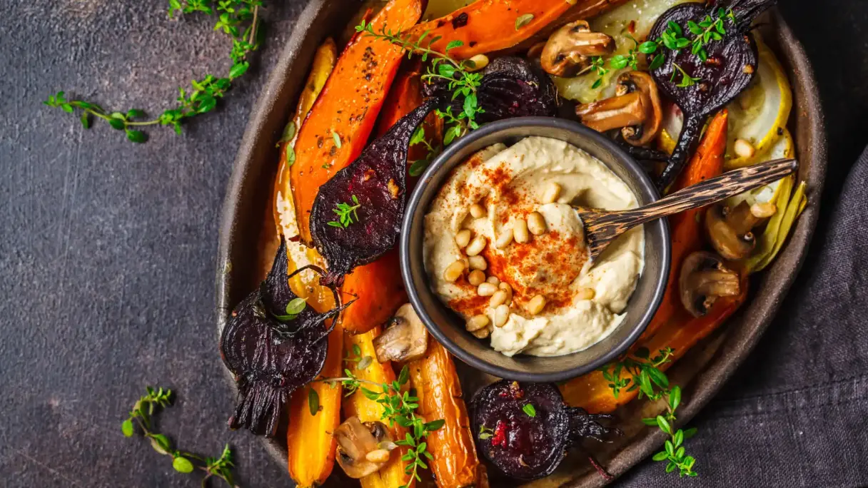 Hummus mit verschiedenem Gemüse in einem Teller.