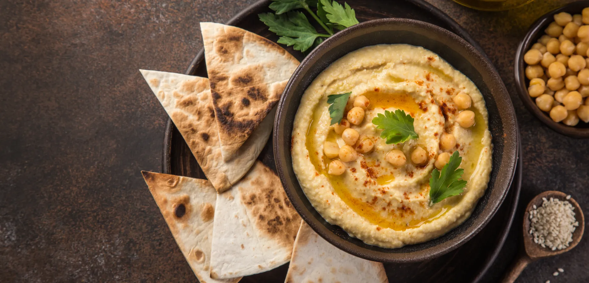 Hummus in einer Schale mit Brotscheiben daneben.