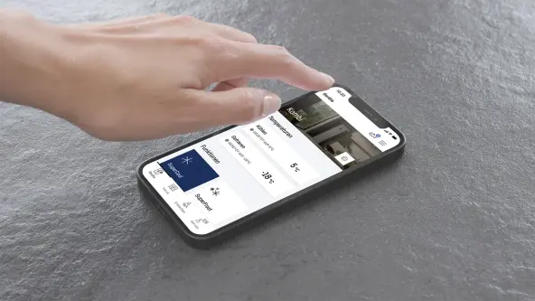 SmartDevice-App: Kühlgerät bequem per Smartphone steuern Hand bedient ein Smartphone mit der SmartDevice‑App; auf dem Display sind Temperaturbereiche und Funktionen eines Kombigeräts zu sehen.
