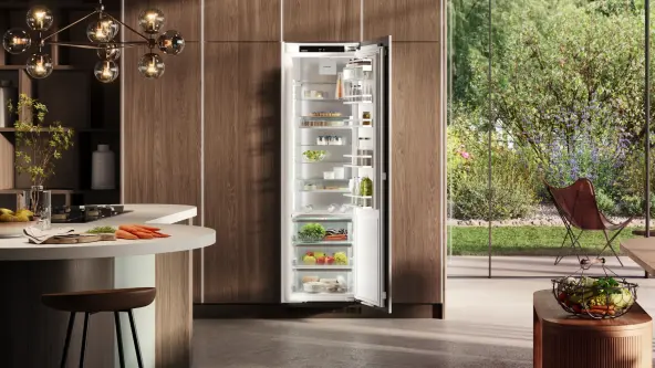 Offener XL-Einbaukühlschrank in moderner Holzküche und Fenster mit Blick in einen Garten