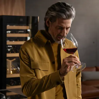 Genussmoment mit Rotwein: Person vor 2-Zonen-Weinkühlschrank riecht am Glas – stilvoll temperiert.
