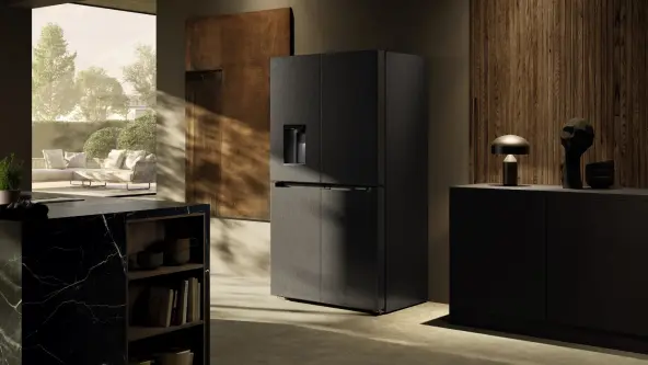 A closed freestanding French Door fridge set in a modern, dark brown and black kitchen
