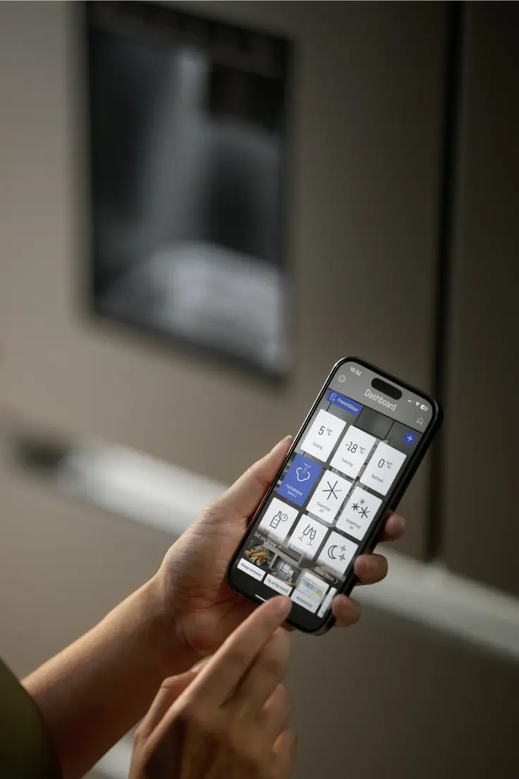 Person holding a smartphone  in their hands and using the SmartDevice App to control their fridge