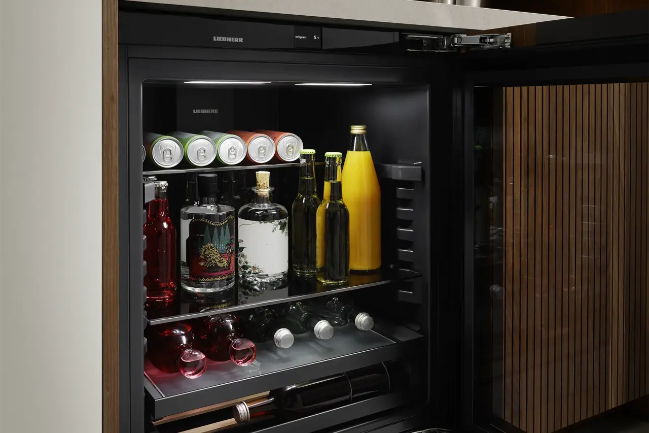 Detailansicht in geöffneten Unterbau-Getränkekühlschrank mit verschiedenen Getränken in Glasflaschen und Dosen