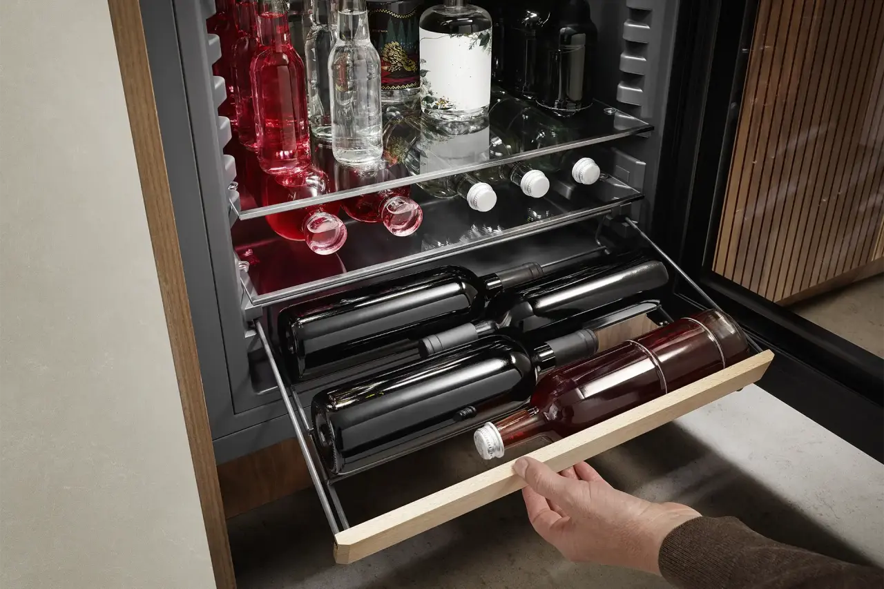 Person zieht mit einer Hand an ausziehbarem Regalbord im BlackSteel Look mit Buchenholzzierleiste, Flaschen darauf