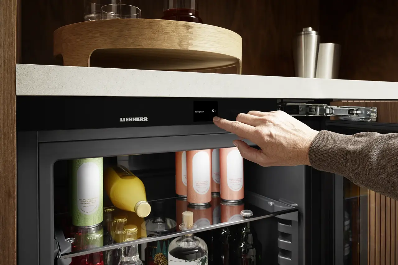 Geöffneter Unterbau-Getränkekühlschrank mit Hand, die Einstellungen über das Touch-Display vornimmt.