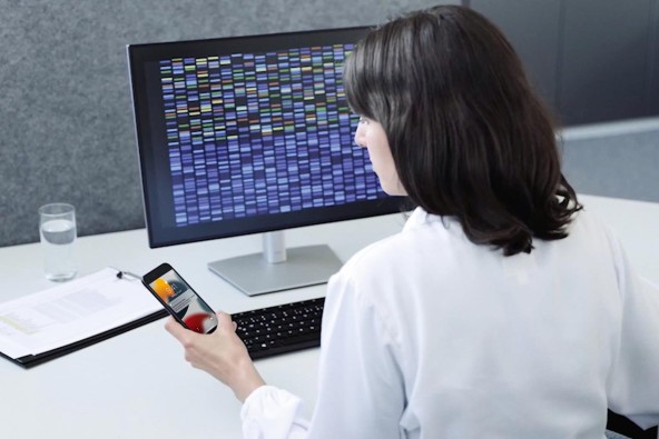 A woman works on digital solutions from Liebherr on a PC and holds a smartphone in her hand A woman works on digital solutions from Liebherr on a PC and holds a smartphone in her hand