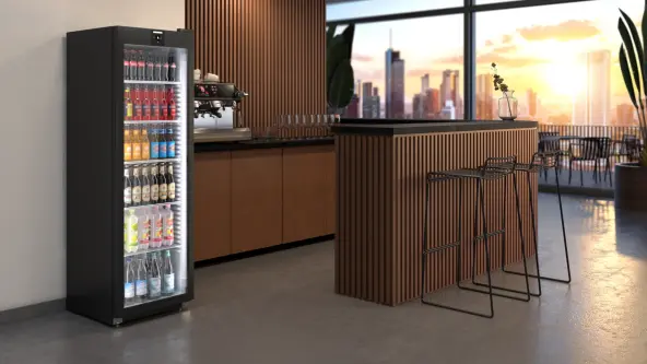 Getränkekühlschrank mit Glastür steht in moderner Rooftopbar mit Ausblick auf eine Großstadt