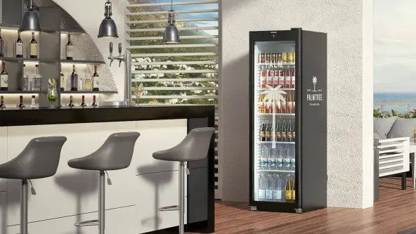 Schwarzer Getränkekühlschrank mit individuell bedrucktem Gehäuse, gefüllt mit Getränken, neben moderner Bar und Hockern.